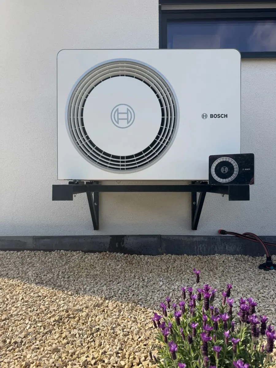 Außeneinheit einer Bosch-Wärmepumpe auf einer Wandkonsole über einem Kiesbeet mit Lavendel; Luft-/Wasser-Wärmepumpe in Hainfeld